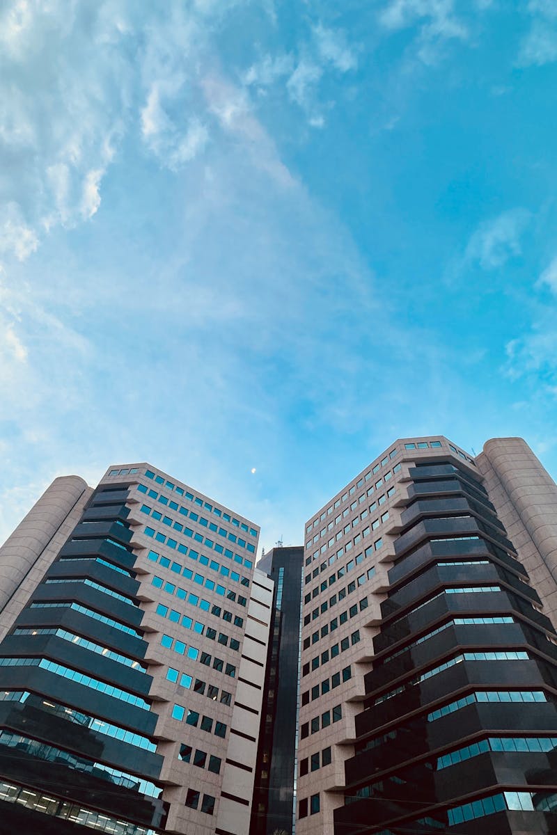 Symmetrical modern office buildings set against a vibrant blue sky.